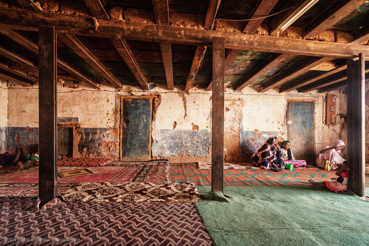 Rustic room with mats, women and children sitting